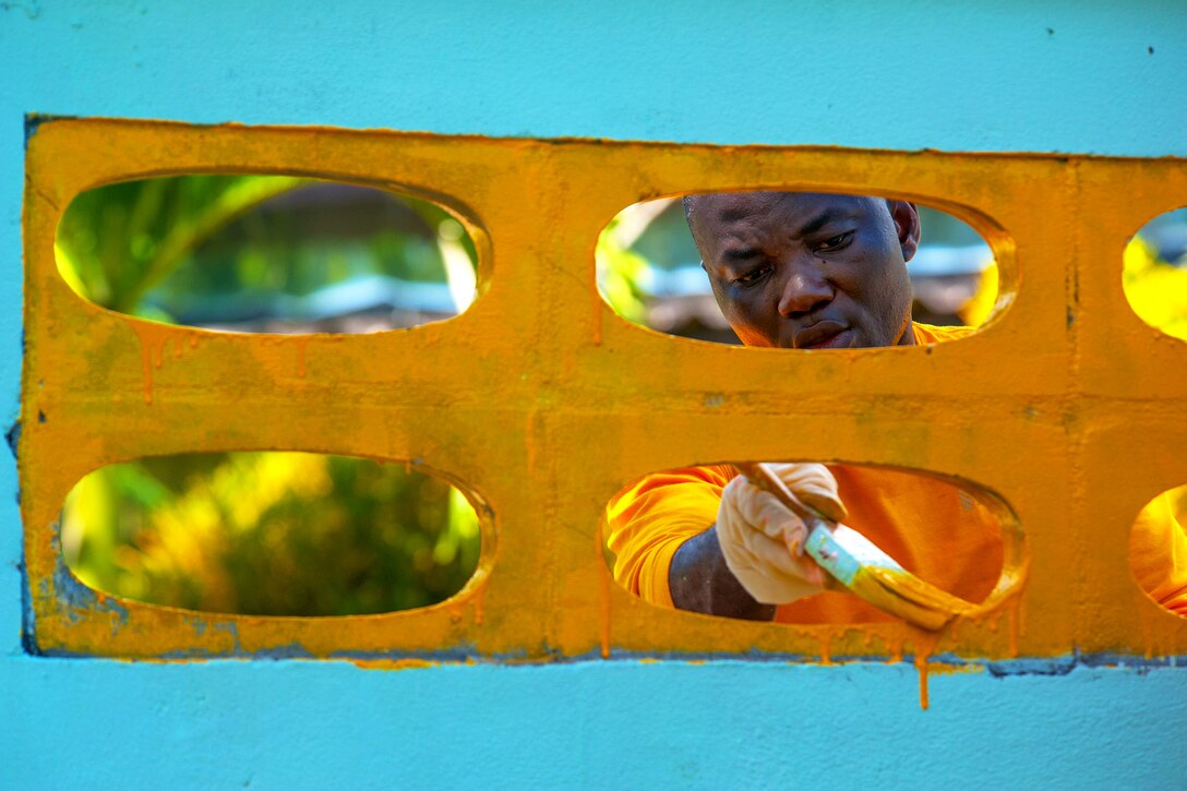 U.S. Navy Petty Officer 3rd Class Robert Appiah helps paint the wall that surrounds the Baan Klong Sai school during a community service project in Phuket, Thailand, Oct. 10, 2012. Appiah, a logistics specialist, is assigned to the USS Mobile Bay.