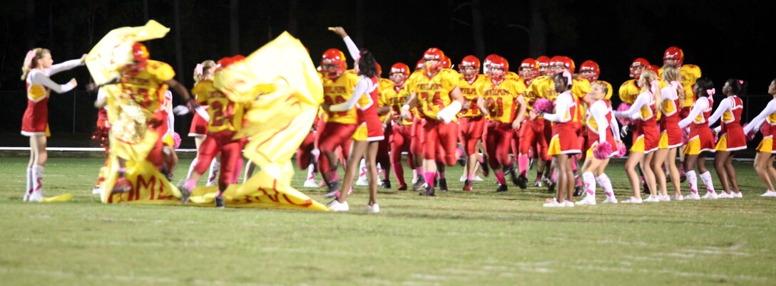 The Lejeune High School Devil Pups storm through a sign as they take the field against Pamlico County High School Friday during Lejeune High’s homecoming game aboard Marine Corps Base Camp Lejeune. The team ran onto the field with a lot of intensity, which transferred over to the scoreboard as the game went on. (Official Marine Corps photo by Lance Cpl. Scott W. Whiting) 