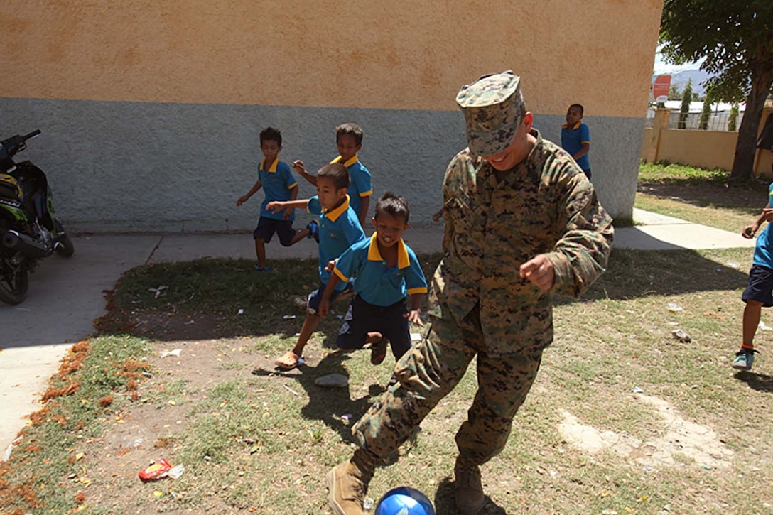 Staff Sgt. Fernando Martinez, motor transportation, Battalion Landing Team 3/5, 15th Marine Expeditionary Unit, kicks a soccer ball with children Escola Primaria Nuu Laran in Dili, Timor-Leste. The MEU and the Peleliu Amphibious Ready Group are in the country conducting Exercise Crocodilo 12, a scheduled exercise to promote interoperability and cooperation between the US and Timor-Leste. Martinez, 38, is from Queens, N.Y.