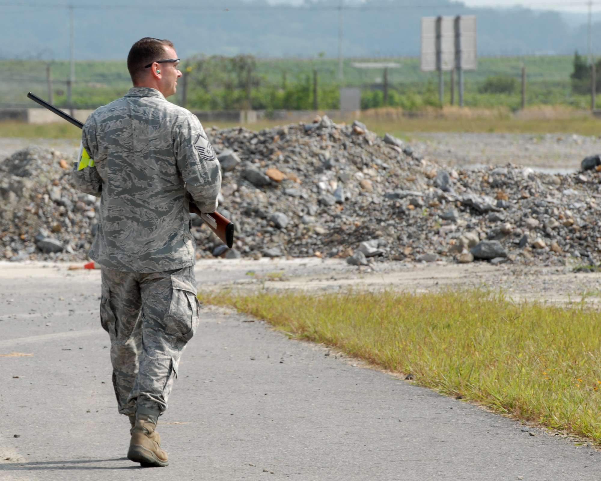 Master Sgt. Keith Kollasch, 8th Fighter Wing NCO of flight safety, cautiously approaches a fence line with shotgun in tow, to rid the air space of birds, Sept. 11, 2012 at Kunsan Air Base, Republic of Korea. Most birds will fly off once a vehicle stops, but some will turn back. There have been 33 Air Force aircraft bird strikes to date, so flight safety members exhaust appropriate depredation methods to prevent future accidents. (U.S. Air Force photo/ Staff Sgt. Tong Duong)