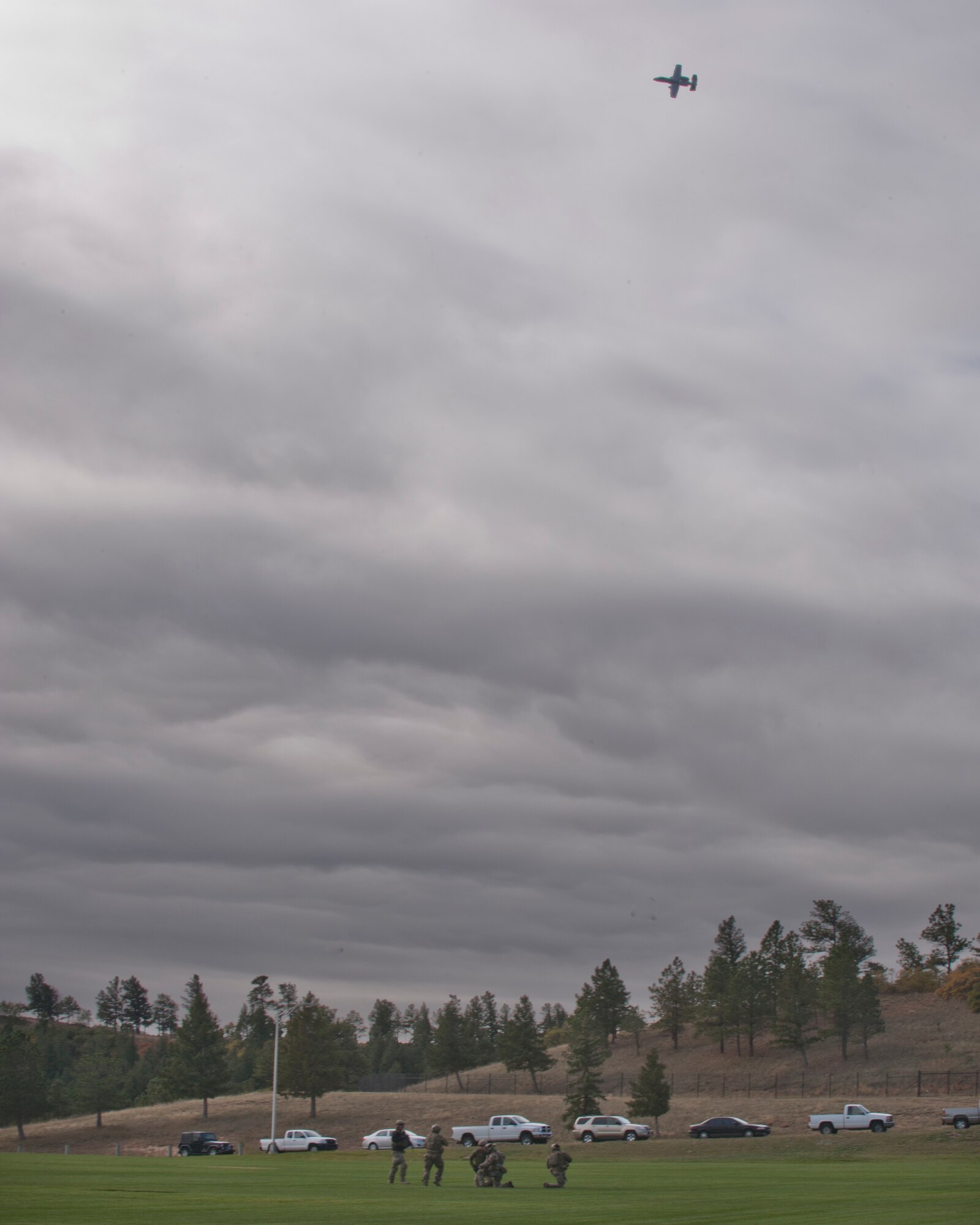 An A-10C Thunderbolt II soars overhead as pararescuemen secure the area during personnel recovery training at the U.S. Air Force Academy, Colo., Oct. 4, 2012. After securing the area, the pararescuemen trained to extract a downed pilot in preparation for a personnel recovery demonstration. (U.S. Air Force photo by Senior Airman Nicholas Benroth/Released)