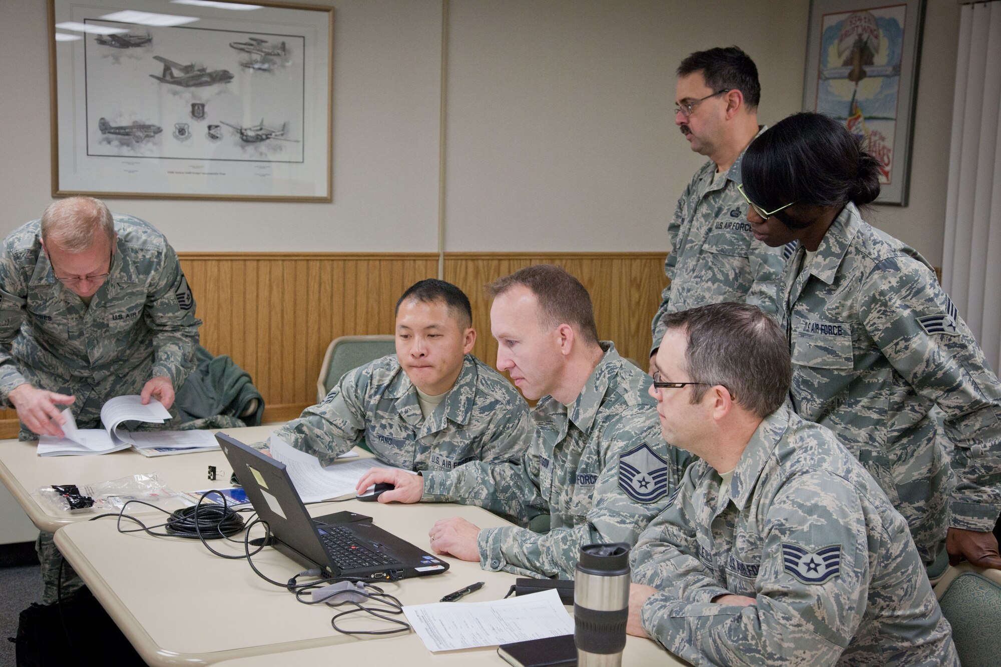 Airmen from the 934th Airlift Wing, from left to right, Master Sgt. Louis Herbes, Senior Airman Toua Yang, Master Sgt. Ross Knutson, Staff Sgt. Geoff Tisdale, (standing) Master Sgt. Gregory Harper, and Senior Airman Nicole Reed, participate in Personnel Support for Contingency Operations training over the Unit Training Assembly weekend.  After nine months of training, they test what they've learned in a hands on excercise of real life situations, from lost ID tags to earning medals, in a simulated deployed location.  (U.S. Air Force Photo/Shannon McKay)