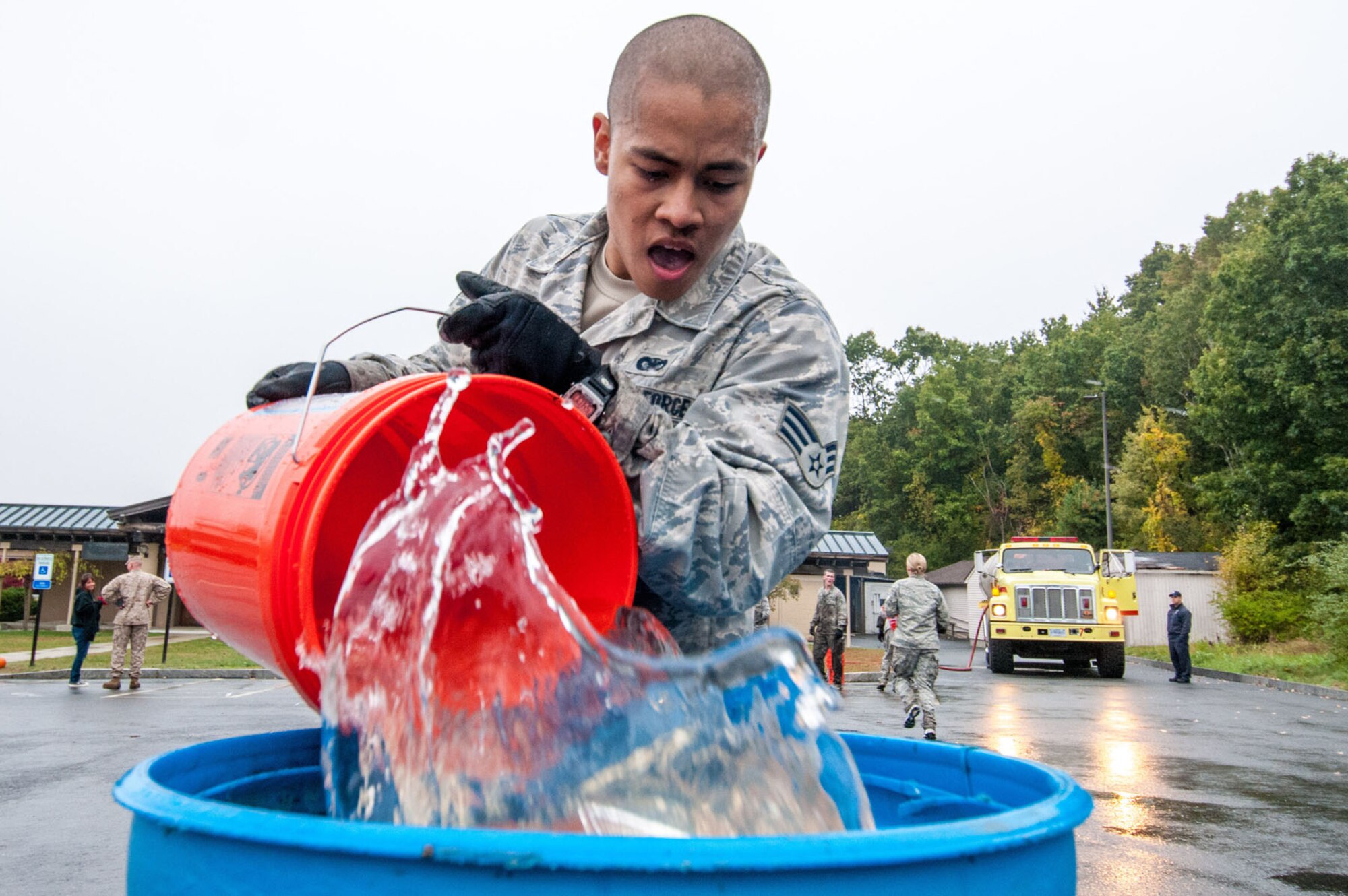 HANSCOM AIR FORCE BASE, Mass. – Senior Airman Francisco Trejo pours water into a larger container Oct. 10 during a Warrior Day obstacle that required competitors to fill the container with water before advancing to the next task. Teams competed in the monthly warrior event that invited other branches of the armed forces to compete. (U.S. Air Force photo by Rick Berry)