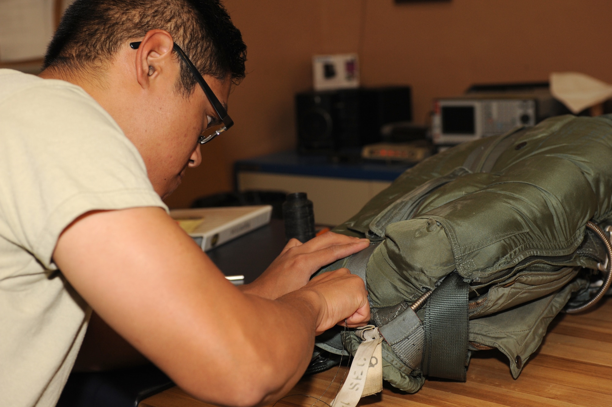 U.S. Air Force Airman 1st Class Daniel Ramos, 563rd Operations Support Squadron aircrew flight equipment technician, repairs a strap on a back style automatic-18 parachute during a 30-day inspection on Davis-Monthan Air Force Base, Ariz., Sept 24, 2012. The 30-day inspection is used to make sure that all prepositioned safety equipment is functional and up to date for inspections. (U.S. Air Force photo by Senior Airman Timothy Moore/Released)