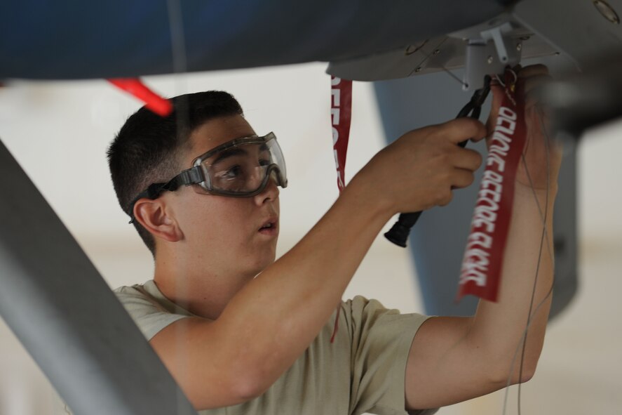 A weapons loader assigned to the 432d Maintenance Group safety wires bolts in place on a MQ-9 Reaper remotely during the 432d MXG load crew of the quarter competition, Oct. 5, 2012, at Creech Air Force Base, Nev. The competition brings together two three-man weapons loading teams from Tiger and Reaper aircraft maintenance units at Creech to compete against each other for top honors. (U.S. Air Force photo by 432d Wing/432d Air Expeditionary Wing Public Affairs)