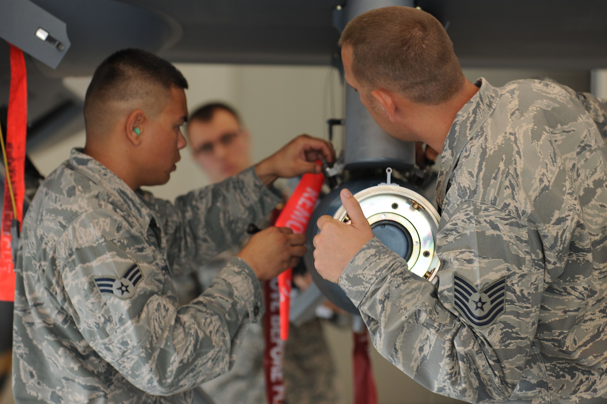 Weapons loaders assigned to the 432d Maintenance Group load a GBU-12 Paveway II laser guided munitions on a MQ-9 Reaper while an inspector judges for accuracy and safety during the 432d MXG load crew of the quarter competition at Creech Air Force Base, Nev. The competition brings together two three-man weapons loading teams from two maintenance units at Creech to compete against each other to show who is the best. (U.S. Air Force photo by 432d Wing/432d Air Expeditionary Wing Public Affairs)