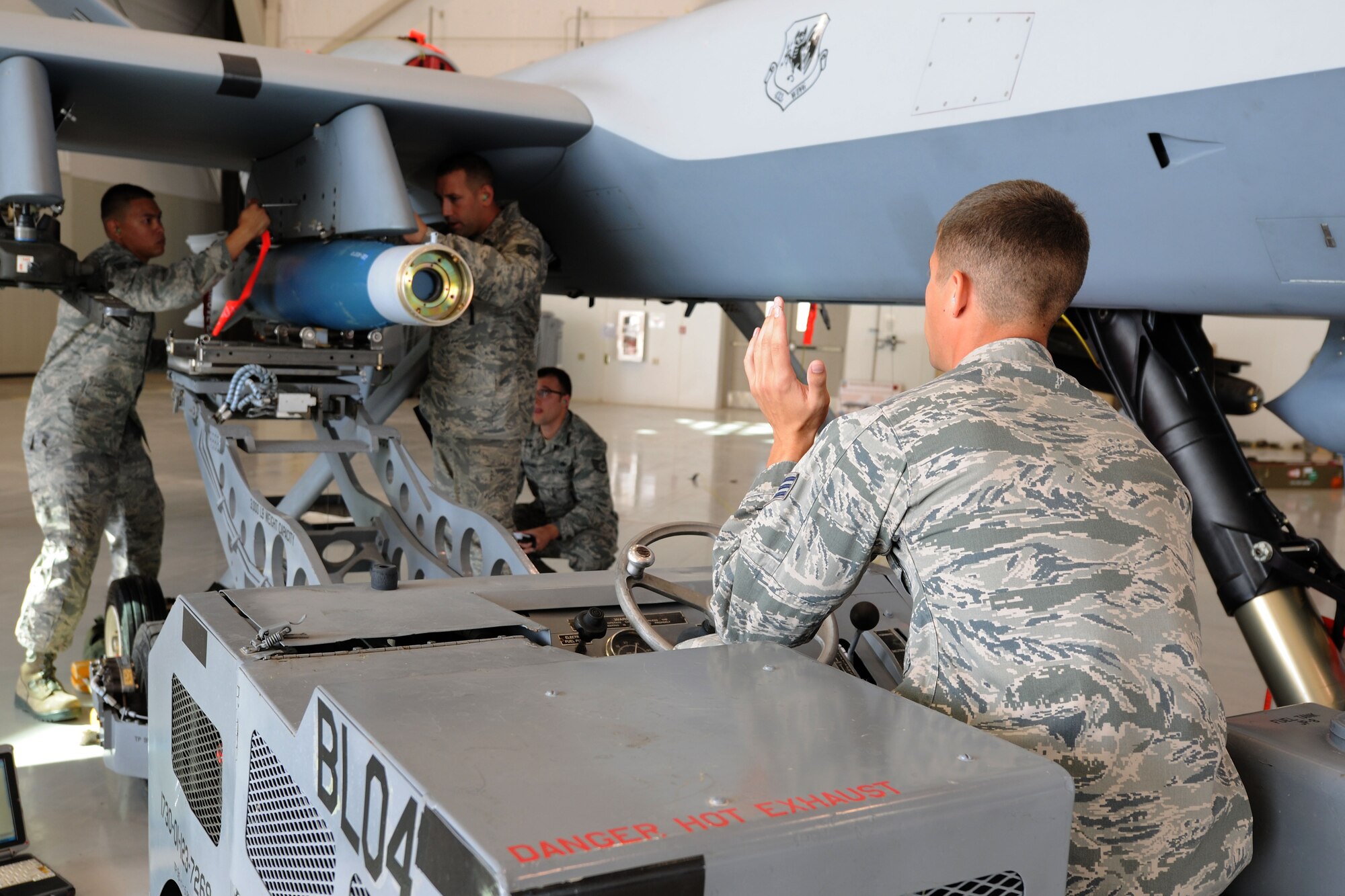 Weapons loaders with the 432d Maintenance Group work together to load a GBU-12 Paveway II laser guided munitions onto a MQ-9 Reaper as an inspector evaluates their progress during the 432d MXG load crew of the quarter competition, Oct. 5, 2012, at Creech Air Force Base, Nev.  The competition brings together two three-man weapons loading teams from Tiger and Reaper aircraft maintenance units at Creech to compete against each other for top honors. (U.S. Air Force photo by 432d Wing/432d Air Expeditionary Wing Public Affairs)