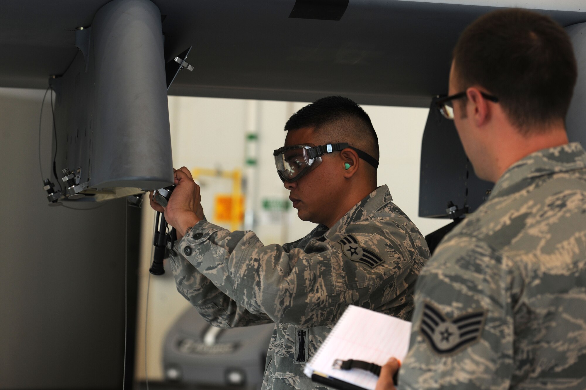 A weapons loader assigned to the 432d Maintenance Group safety wires bolts in place on a MQ-9 Reaper while an inspector judges for accuracy and safety during the 432d MXG load crew of the quarter competition, Oct. 5, 2012, at Creech Air Force Base, Nev. The competition brings together two three-man weapons loading teams from Tiger and Reaper aircraft maintenance units at Creech to compete against each other for top honors. (U.S. Air Force photo by 432d Wing/432d Air Expeditionary Wing Public Affairs)