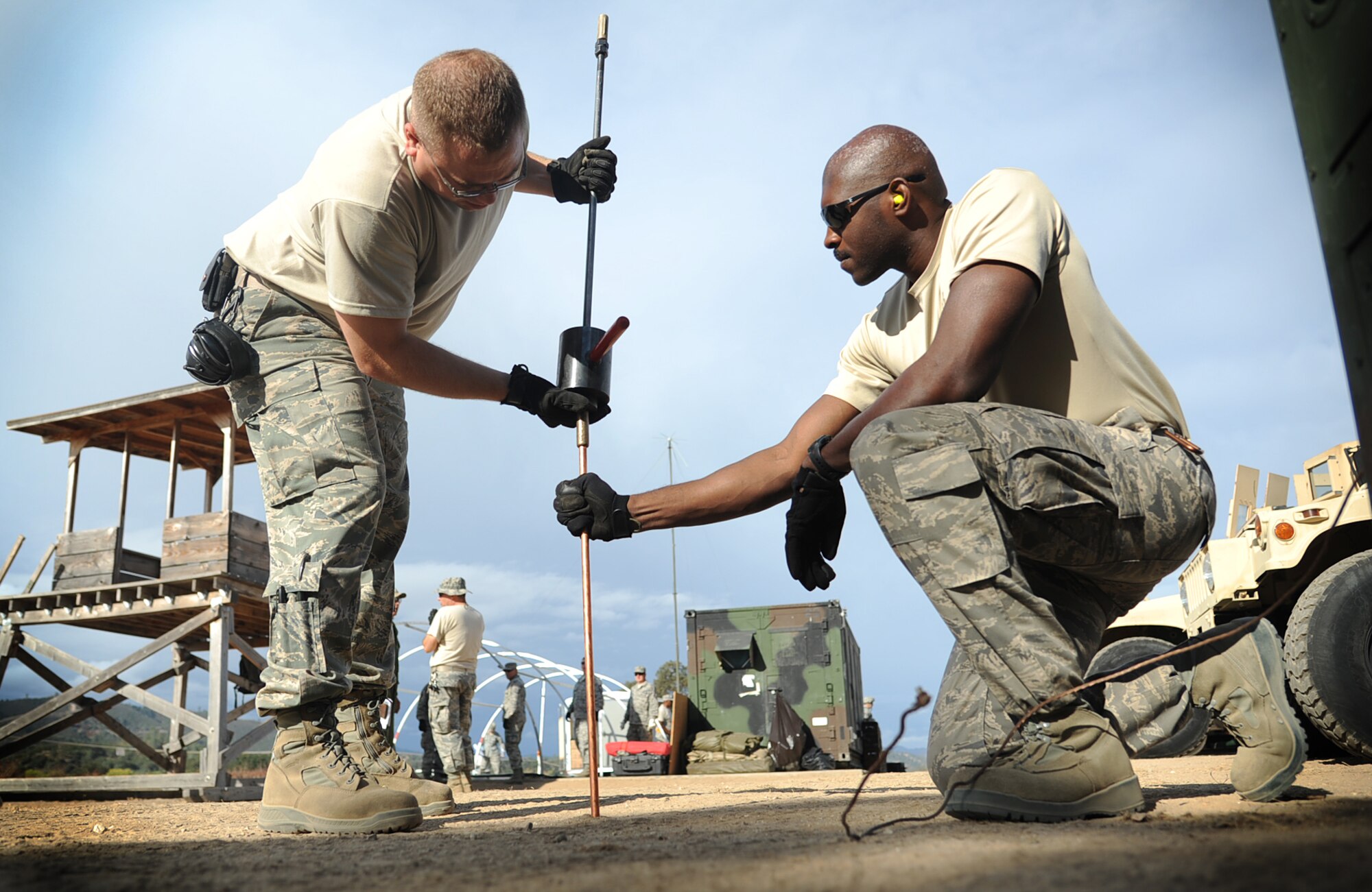 Staff Sgt. James Ausmus and Senior Airman Geoffrey Walker (l to r), both assigned to the 573rd Global Support Squadron, pound in a generator grounding rod at the U.S. Army Combat Support Training Center at Fort Hunter Liggett, Calif. during Exercise Soaring Angel.  Members of the 621st Contingency Response Wing and the 129th Rescue Wing, partnered to get crucial training at the installation’s Schoonover LZ. (U.S. Air Force Photo/MSgt Stan Parker)