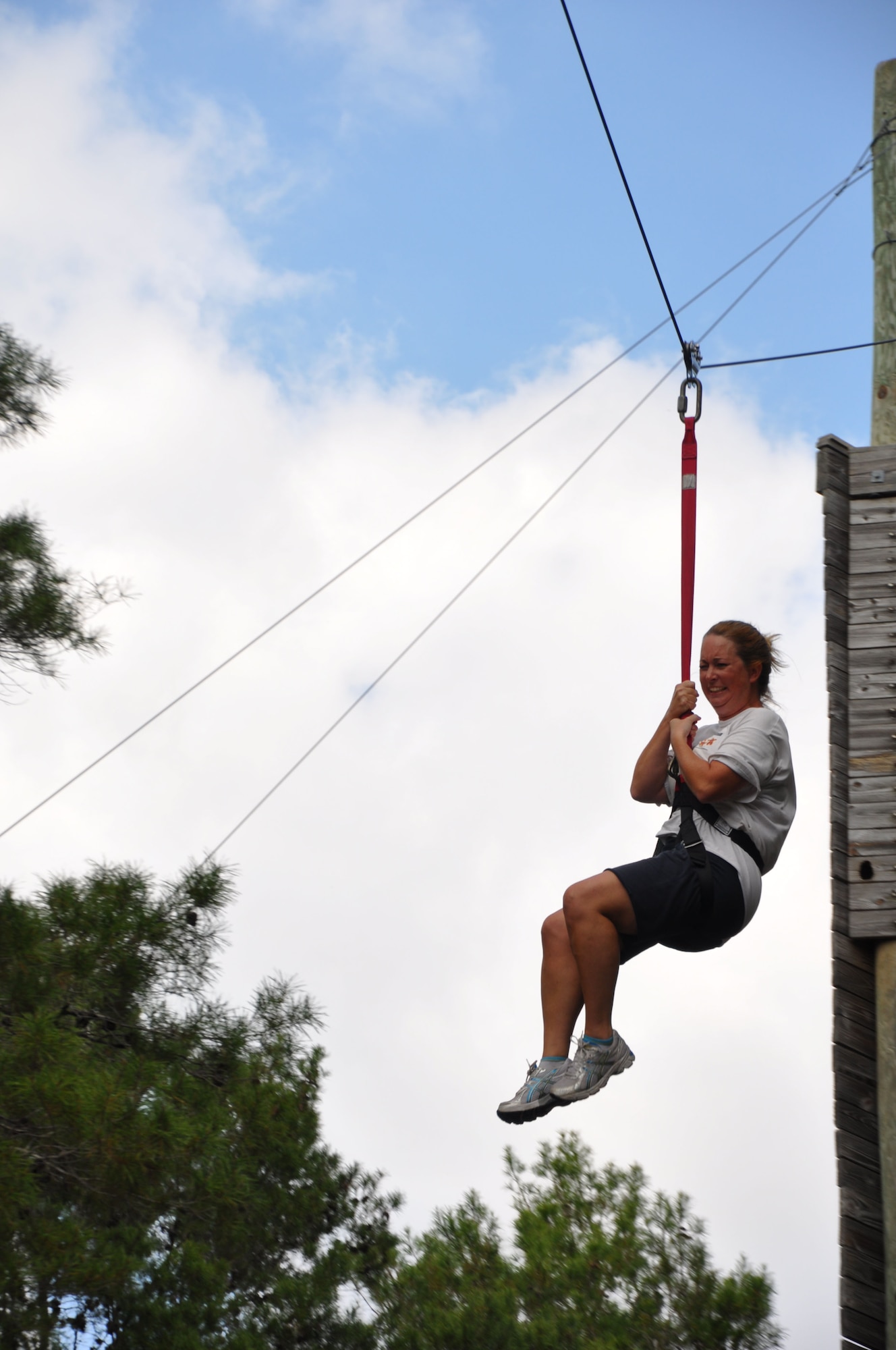 Julie Miller, Leadership Bay participant, zips down from a 55-foot tower at the Tyndall Ropes Course Oct. 13. Leadership Bay, a subgroup of the Bay County Chamber of Commerce, spent the day completing tasks designed to foster teambuilding. The ropes course is operated by Bonita Bay and run by volunteers. (U.S. Air Force Photo by Ashley M. Wright)