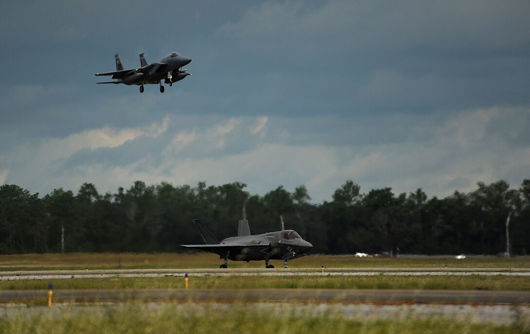 An F-35B Lightning II joint strike fighter from the Marine Fighter Attack Training Squadron 501, Eglin Air Force Base, Fla.,  sits on the runway waiting for take off clearence for a local training mission over the Emerald Coast Sept. 18, 2012 while an Air Force F-15 Eagles prepares to land.

