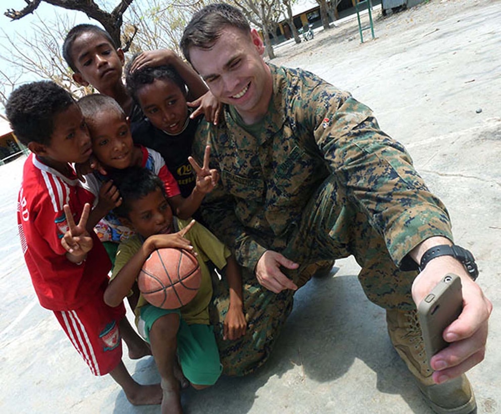 Staff Sgt. Harry G. Prassenos, operations chief, Military Information Support Operations Detachment, 15th Marine Expeditionary Unit, takes a picture with Timorese children after fellow Marines and sailors presented books, school supplies and sporting goods to their elementary school in Manatuto, Timor-Leste, Oct. 14. The donations were part of a community relations program supporting Exercise Crocodilo 2012, a U.S./Timor-Leste event promoting interoperability and regional stability.