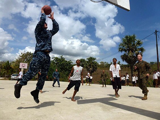Petty Officer 1st Class Edward S. Debaun (right), religious program specialist, Command Element, 15th Marine Expeditionary Unit, and Petty Officer 2nd Class Canon L. Deimerly, operations specialist, Amphibious Squadron Three, play a game of basketball against Timorese students after fellow Marines and sailors presented books, school supplies and sporting goods to their elementary school in Baucau, Timor-Leste, Oct. 15. The donations were part of a community relations program supporting Exercise Crocodilo 2012, a U.S./Timor-Leste event promoting interoperability and regional stability.
