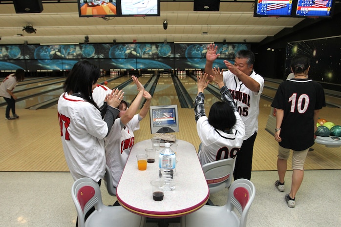 Marine Corps Community Services employees give high-fives in celebration of a strike during the MCCS employees day of play here at the Strike Zone bowling alley Oct. 10, 2012. The employees divided into random teams
to allow members of each section to get to know someone new or with they were not familiar with.