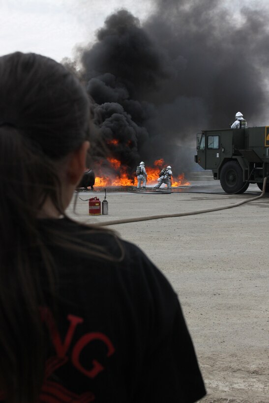 A young warrior stands and watches as Aircraft Rescue Fire Fighting Marines put out a fire at the ARFF burn pit here during Young Warrior Day Oct. 13, 2012. Young Warrior Day allowed children of servicemembers to experience what their parents do in the military. 