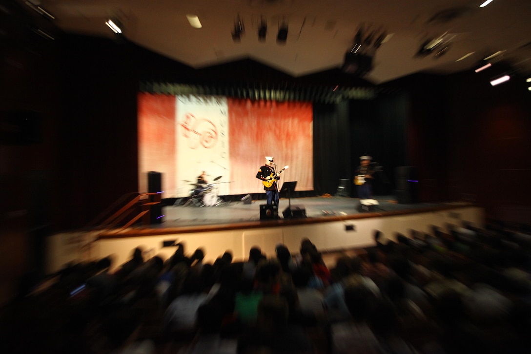 Lance Cpl. David Corderman of Richmond, Va., sings in front of hundreds of high school students. He and two other Marines within the band took the initiative to come together and form the 2nd Marine Division rock band. 