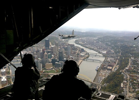 During a C-130H2 formation training exercise, Tech Sgt. Christine Jones, a photographer from the 4th Combat Camera squadron, March Air Reserve Base, Calif., receives in-flight instructions from Tech Sgt. Jackie Kupetz, a loadmaster with the 758th Airlift Squadron while flying over Pittsburgh, Pa., Oct. 18, 2012.  Jones’ first-time aerial photography training included shooting still photos from the C-130s ramp and ‘troop’ or side doors, while aircrew members trained on a variety of tactics to include; two-ship formations, run-ins, and low-level routes. The Fall foliage created a picturesque backdrop, which further added to the uniqueness of Jones' first-time Southwestern Pa. experience. The mission of Combat Camera (COMCAM) is to acquire still and motion imagery in support of classified and unclassified air, sea, and ground military operations. The mission of the 911th Airlift Wing is to organize, recruit and train Air Force Reserve personnel and to provide airlift of airborne forces, their equipment and supplies and delivery of these forces and materials by airdrop or airland operations. (U.S. Air Force photo by Senior Airman David Vanik, 758th Airlift Squadron/Released)