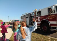 Military children wave to a convoy of fire trucks and emergency response vehicles taking part in the 2012 Fire Prevention Week Parade Oct. 12, 2012, on Grand Forks Air Force Base, N.D.  The parade was the final event of a week-long series of activities during FPW, which focused on educating people on having an escape plan with two exits in a fire emergency. (U.S. Air Force photo/Airman 1st Class Xavier Navarro) 
