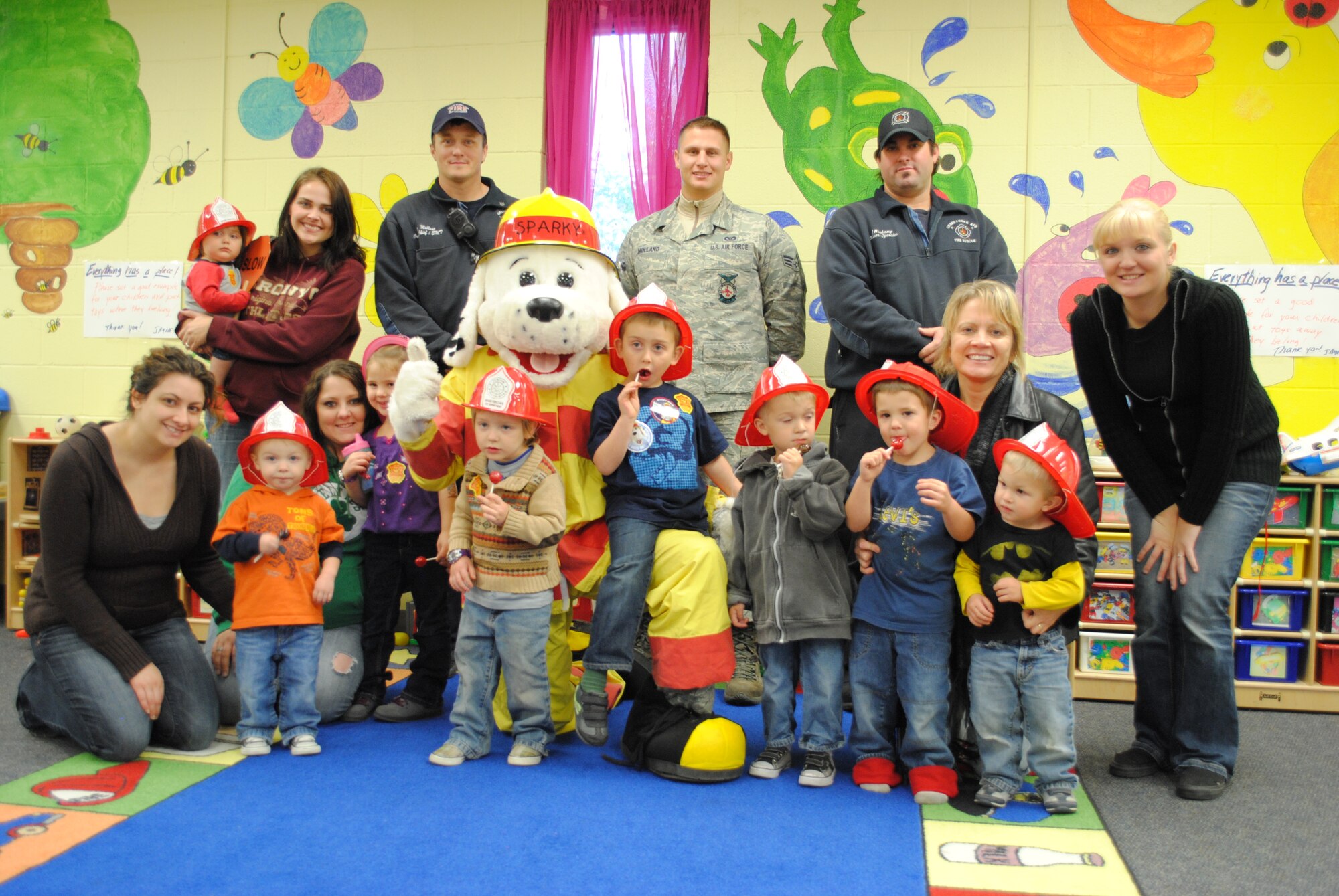 Military children, parents, staff members, base fire department personnel and Sparky the Fire Dog pose for a group photo Oct. 12, 2012, at the Adult Child Center on Grand Forks Air Force Base, N.D. Oct. 12, 2012.  National Fire Prevention Week is conducted nationally during the second week in October with the purpose of educating the public on fire safety. The Grand Forks AFB Fire Department supports this national education initiative by hosting multiple events and visiting local schools to educate all ages about the danger of fire. To kick off the week’s festivities, Col. Timothy Bush, 319th Air Base Wing commander, signed the 2012 Fire Prevention Week proclamation alongside Sparky. Senior Airman Timothy Jordan, a fire protection journeyman from the 319th Civil Engineer Squadron, dressed up as Sparky for this event. (U.S. Air Force photo/Senior Airman Luis Loza Gutierrez)