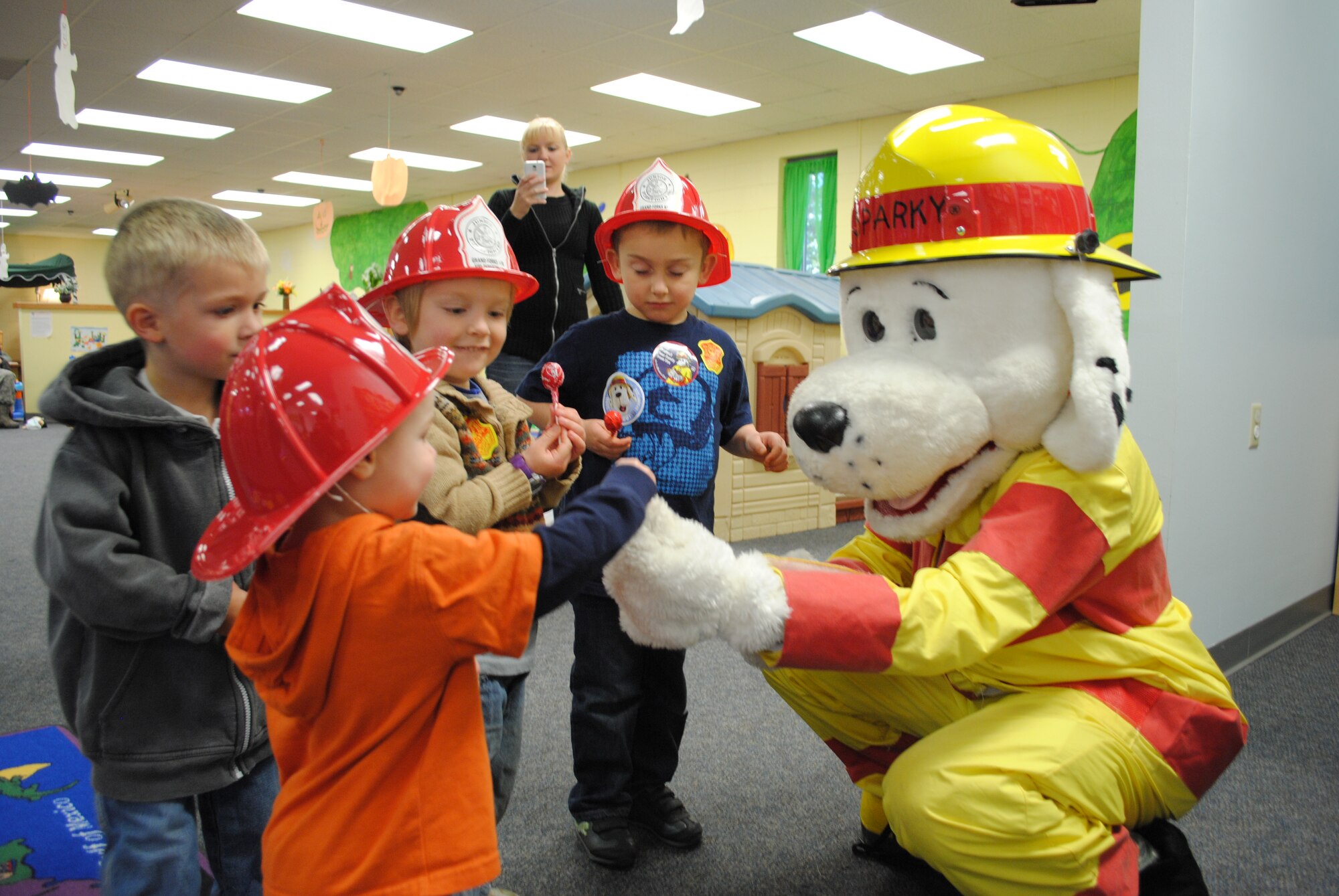 Children rush to get candy treats from Sparky the Fire Dog, who visited the Parent Child Center during Fire Prevention Week on Grand Forks Air Force Base, N.D. Oct. 12, 2012.  Fire Prevention Week is conducted nationally during the second week in October with the purpose of educating the public on fire safety. The Grand Forks AFB Fire Department supports this national education initiative by hosting multiple events and visiting local schools to educate all ages about the danger of fire. To kick off the week’s festivities, Col. Timothy Bush, 319th Air Base Wing commander, signed the 2012 Fire Prevention Week proclamation alongside Sparky. Senior Airman Timothy Jordan, a fire protection journeyman from the 319th Civil Engineer Squadron, dressed up as Sparky for this event. (U.S. Air Force photo/Senior Airman Luis Loza Gutierrez)