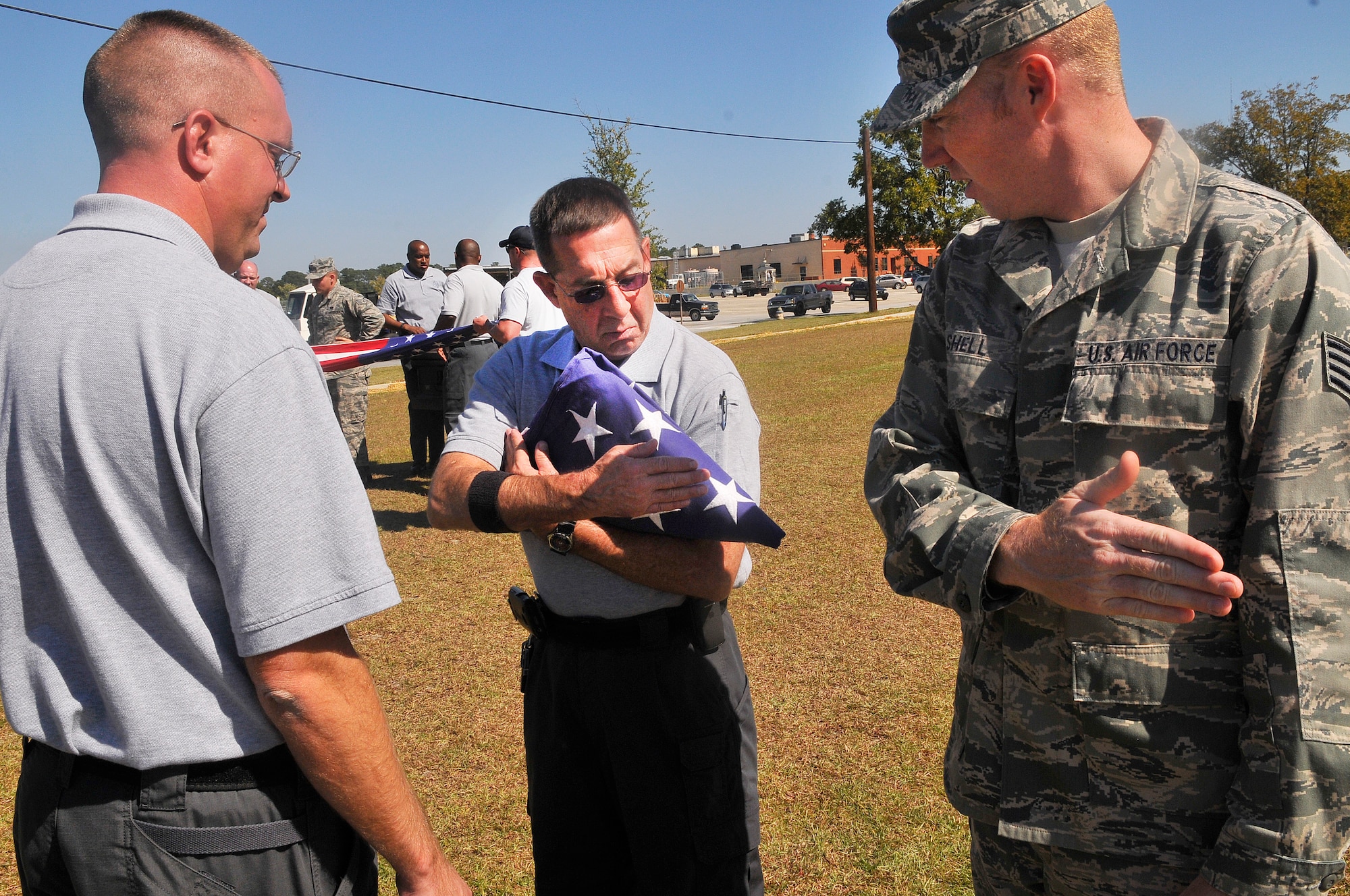 L-R, MCO3 Wesley Willis and Sgt. Al McFarlin, Georgia State Patrol, get instruction from Staff Sgt. Jonathan Shell on handling a folded flag. Thirty One Georgia State Patrol honor guard members from around the state trained with the Robins Air Force Base Honor Guard Oct. 16-17.(U. S. Air Force photo/Sue Sapp)