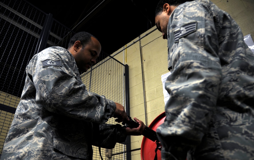 Staff Sgt. Patrick First, 509th Logistics Readiness Squadron weapons supervisor, practices the procedure of assigning an M-16 to a deploying member at Whiteman Air Force Base, Mo., Oct. 15. Weapon handlers must be armed with an M-9 and follow strict guidelines while giving a weapon to a deploying member. (U.S. Air Force photo/Senior Airman Cody H. Ramirez)