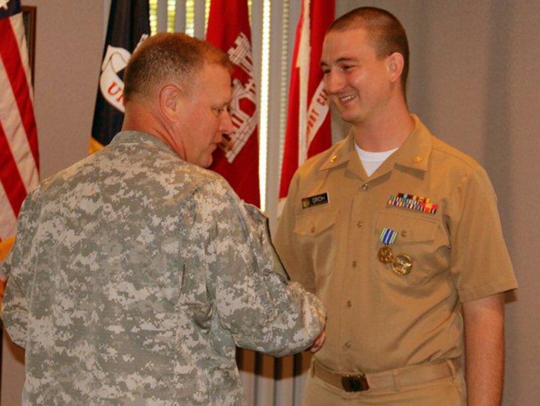 Col. Robert Ruch, Huntsville Center commander, left, presents Lt. Cmdr. Brandon Groh with the Army Achievement Medal. Groh is a civil engineer and an officer in the U.S. Public Health Services Commissioned Corps where he serves the U.S. Army Corps of Engineers as an expert in the field of health care facility construction and renovation.