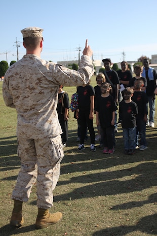 Lt. Col. Lance Lewis, Headquarters and Headquarters Squadron commanding officer, speaks to the participants of Young Warrior Day before handing out the certificates to the children at the end of the day. The children spent the day traveling to the Indoor Small Arms Range to learn about weapons systems, went through gear operation, saw Aircraft Rescue Firefighters perform and put out a fire, ate Meals Ready to Eat, saw a Provost Marshal's Office K-9 demonstration, used camouflage paint on their faces and performed a modified Combat Fitness Test.