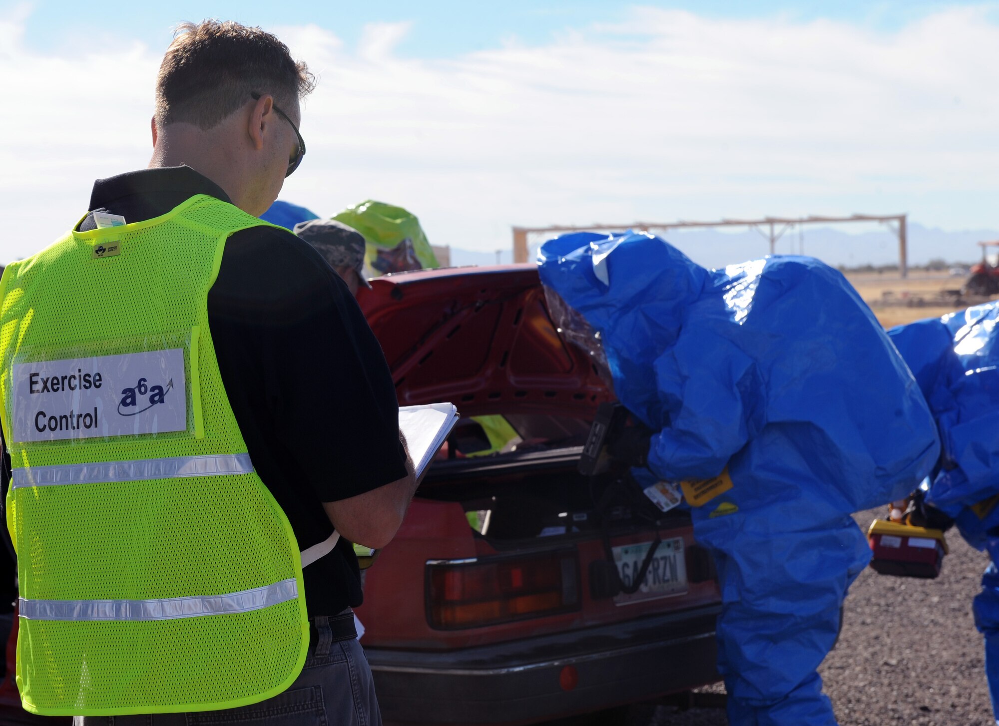 Adam Christmann, A6A Associates, evaluates members of the Bioenvironmental Flight while they check contamination levels on a car after a simulated explosion during the Training and Assessment Program exercise on Davis-Monthan Air Force Base, Oct. 19, 2012. RTAP provides installations with a capability for improving integrated installation emergency response training and assessments for installation Exercise Evaluation Teams and nineteen functional communities. (U.S. Air Force photo by Senior Airman Brittany Dowdle/release)