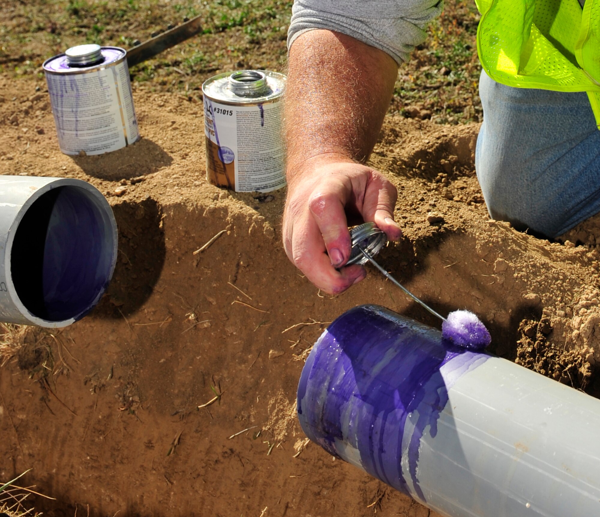 BUCKLEY AIR FORCE BASE, Colo. – Jerald Gilkey, 460th Civil Engineer Squadron high voltage electrician, applies cement to connect two pipes Oct. 16, 2012. The cement is the main substance that holds the pipes together which protects electrical wires for the street lamps. (U.S. Air Force photo by Airman 1st Class Darryl Bolden Jr.)