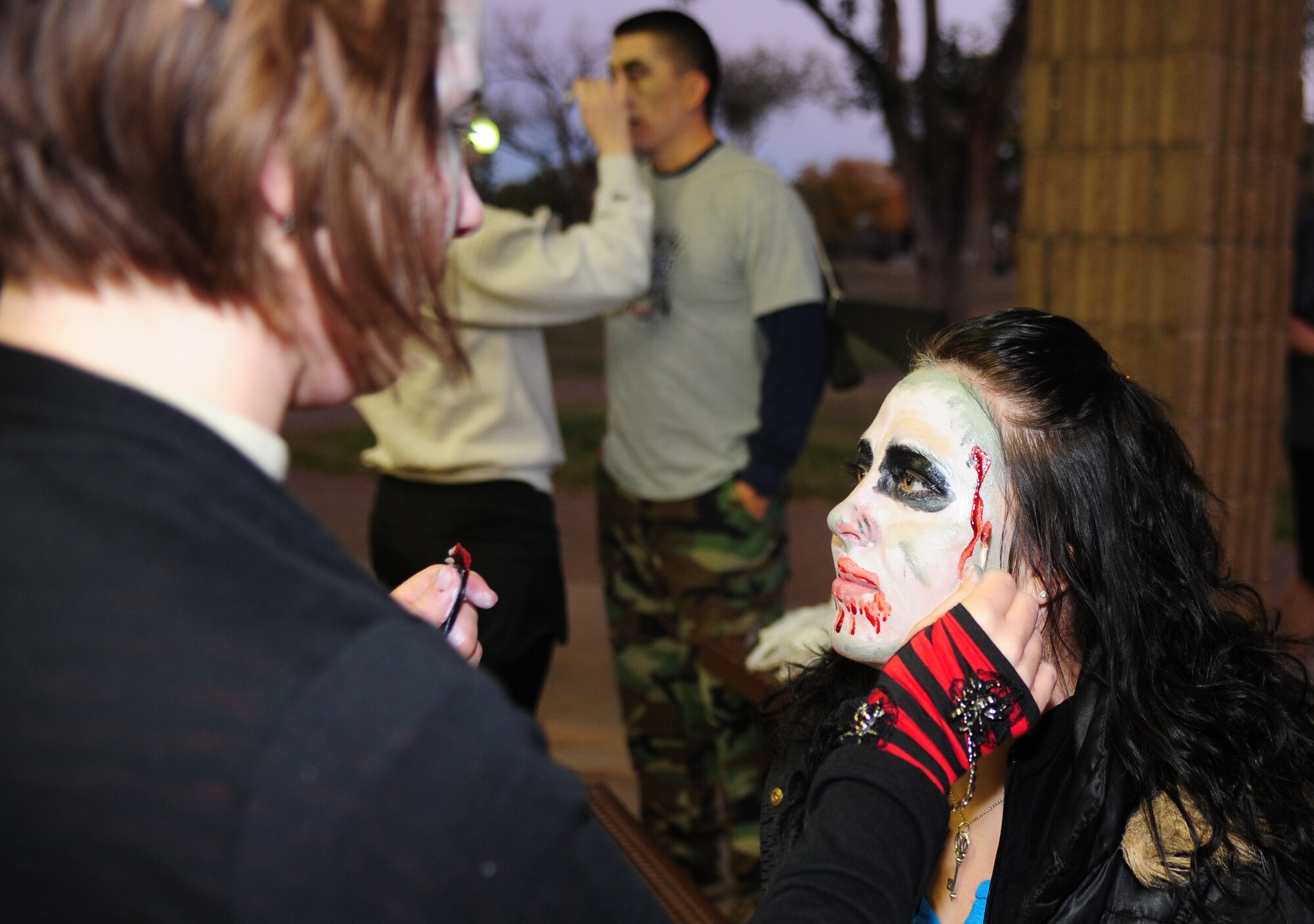 A volunteer puts zombie makeup on Airman 1st Class Samantha Crenshaw, 27th Special Operation Contracting Squadron contract specialist, at the Zombie 5K at Cannon Air Force Base, N.M., Oct. 19, 2012. Personnel volunteered to be transformed into their undead alter egos to hunt down fellow Airmen during the run that encouraged Air Commandos to get involved in the local Air Force First Sergeant’s Association chapter. (U.S. Air Force photo/Airman 1st Class Ericka Engblom)