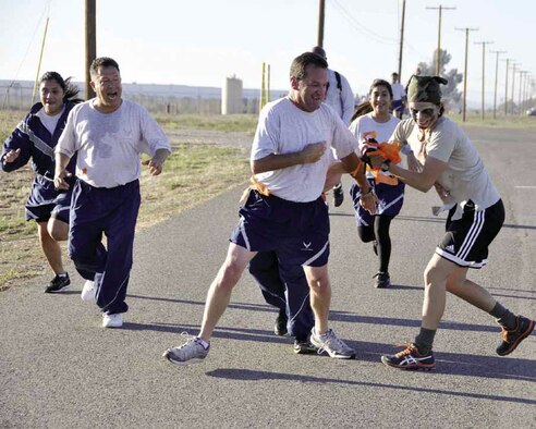 Zombie, Tech. Sgt. Erica Knight, 4th Combat Camera Squadron, attempts to grab a flag from Staff Sgt. Guy La Plante, 4CTCS, during the first March 5K Zombie Run Oct. 14. The 452nd Rising Six organization hosted the run, which they say will become an annual event. (U.S. Air Force photo by Master Sgt. Linda Welz)