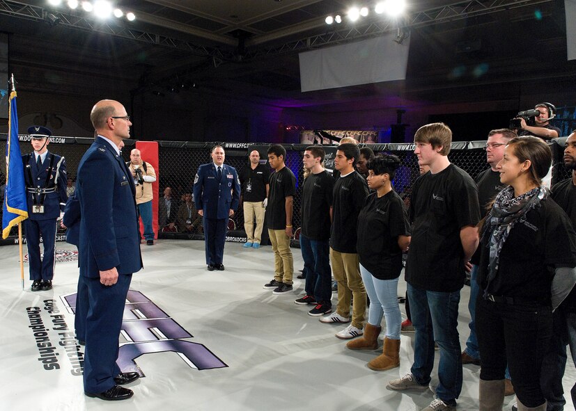 Col. Raymond A. Kozak (left), 512th Airlift Wing commander, stands by while Senior Master Sgt. David Drake (middle), shouts a command to 12 recruits in preparation for a mass enlistment ceremony Oct. 13, 2012, at the Dover Downs' Rollins Center, in Dover, Del. The enlistment ceremony took place inside the caged ring of a professional mixed martial arts event, which was attended by the Ultimate Fighting Championship's Ben Henderson, the current lightweight champion. (U.S. Air Force photo/Roland Balik)