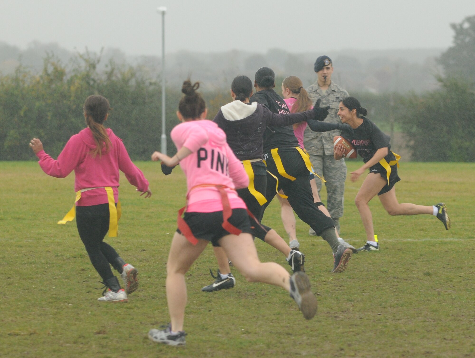 Staff Sgt. Jessica Garcia, 100th Security Forces Squadron, runs with the ball during the Powder Puff football game Oct. 19, 2012, at RAF Mildenhall, England. The game was hosted by members of the 100th Security Forces Squadron to raise awareness of breast cancer and featured all-female teams made up of participants from several units as well as dependants.  (U.S. Air Force photo by Tech. Sgt. Neal X. Joiner/Released) 