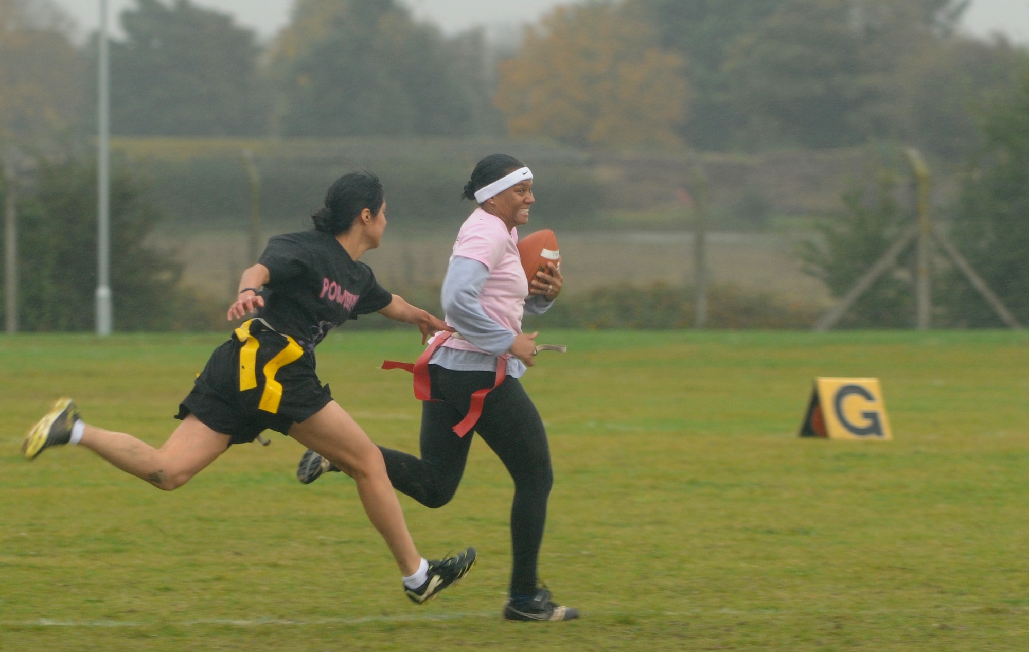 Staff Sgt. Jessica Garcia, 100th Security Forces Squadron, attempts to tear the flag from Master Sgt. Nancy Buchanan, 352nd Special Operations Maintenance Squadron, during the Powder Puff football game Oct. 19, 2012, at RAF Mildenhall, England. The players were members of all-female teams who played to raise awareness of breast cancer. (U.S. Air Force photo by Tech. Sgt. Neal X. Joiner/Released)
