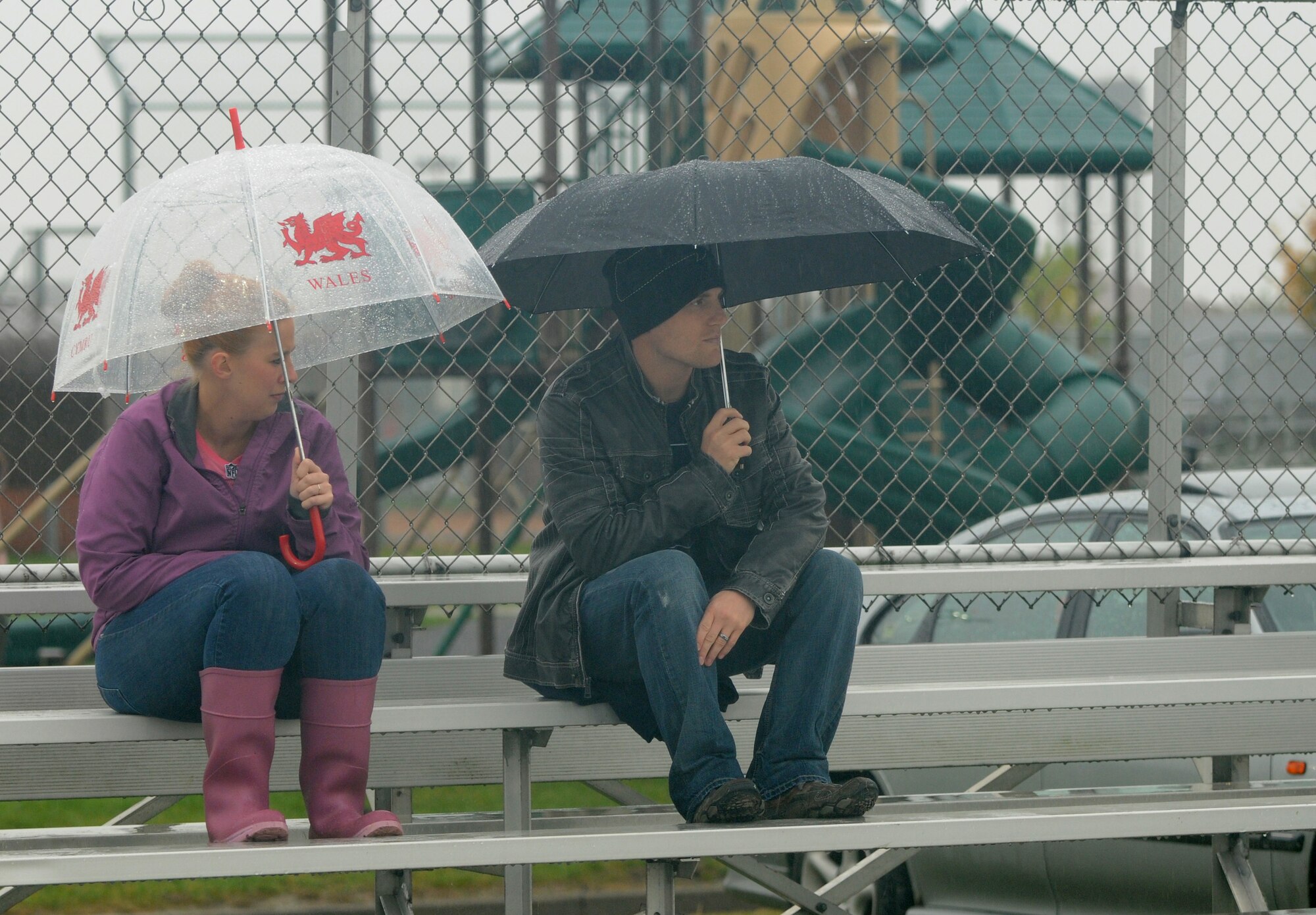 Spectators brave the rain while watching the Powder Puff football game Oct. 19, 2012, at RAF Mildenhall, England. The game was played by all-female teams and hosted by members of the 100th Security Forces Squadron to raise awareness of breast cancer. (U.S. Air Force photo by Tech. Sgt. Neal X. Joiner/Released) 