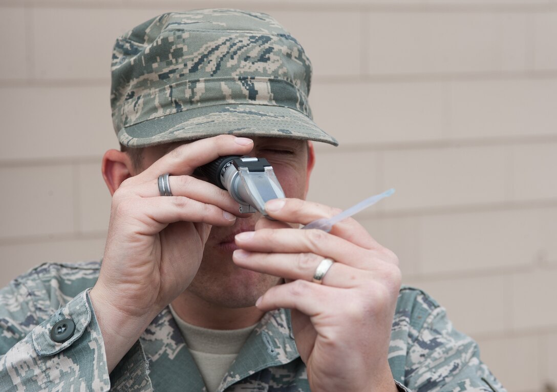 Staff Sgt. Matthew Auger, 28th Civil Engineer Squadron heating, ventilation, and air conditioning technician, looks through a reflectometer to determine the amount of glycol in the water at the engine shop on Ellsworth Air Force Base, S.D., Oct. 16, 2012. The HVAC shop visited buildings around base to add an antifreeze mixture to winterize the closed water systems in order to prevent water from freezing in the pipes and causing equipment damage during the winter. (U.S. Air Force photo by Airman 1st Class Alystria Maurer/Released)