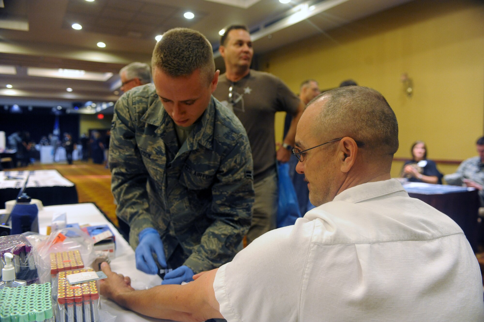 Airman 1st Class Jordan Cook, 56th Medical Operations Squadron medical lab technician, draws blood from Karl Loving, retired Army major, Oct. 12 during the Men’s Health Expo at Club Five-Six. Cook’s booth featured information on men’s health. (U.S. Air Force photo by Airman 1st Class Devante Williams)