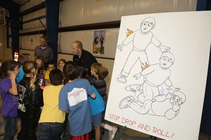 Kenny Shepard, 902nd Civil Engineer Squadron firefighter and emergency medical technician, answers a question from a student at the Randolph Elementary School about the proper stop, drop and roll procedure during a Fire Prevention Week demonstration Oct. 10 at Joint Base San Antonio-Randolph.   (U.S. Air Force photo by Josh Rodriguez)