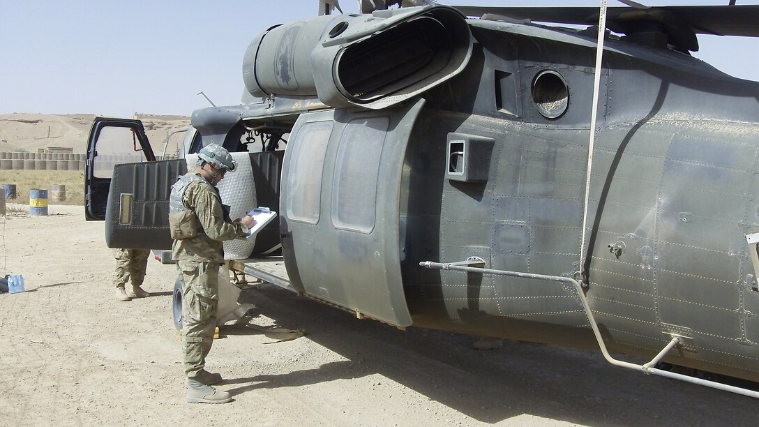 Tech. Sgt. Peter Feliciano Jr., 8th Expeditionary Air Mobility Squadron Air Transportation joint inspector, conducts an inspection of a downed UH-60 Black Hawk helicopter in Forward Operating Base Chakhcharan. Feliciano and the JI team prepared the Black Hawk to ensure all hazardous material and cargo were properly secured so it could be loaded and transported in a C-17 Globemaster III and flown out for repairs. (U.S Air Force courtesy photo)