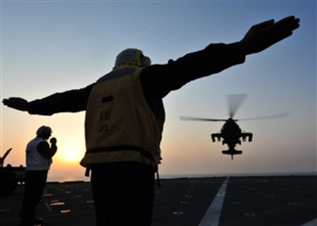 U.S. Navy Petty Officer 3rd Class Jean Petitfrere signals a U.S. Army AH-64 Longbow Apache helicopter to land on the flight deck of the USS Gunston Hall (LSD 44) as the ship steams in the Arabian Sea on Oct. 9, 2012.  Gunston Hall and the embarked 24th Marine Expeditionary Unit are part of the Iwo Jima Amphibious Ready Group which is deployed in support of maritime and theater security operations in the U.S. 5th Fleet area of responsibility.  
