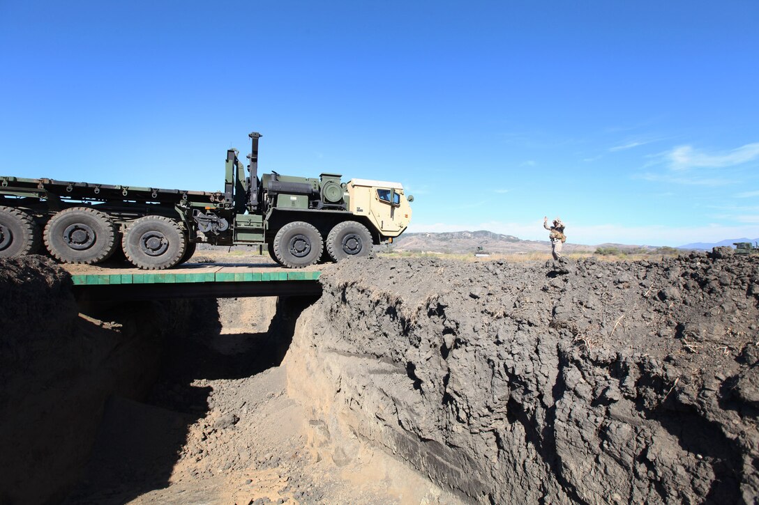 Staff Sgt. Wayne Plew, an operations chief with Bridge Company, 7th Engineer Support Battalion, 1st Marine Logistics Group, directed by Staff Sgt. Timothy Liners, a combat engineer with Bridge Company, drives across a newly constructed non-standard bridge during a field training exercise at Camp Pendleton, Calif., Oct. 15. Plew, 37, is from Filer, Idaho. Liners, 32, is from Lake City, S.C.