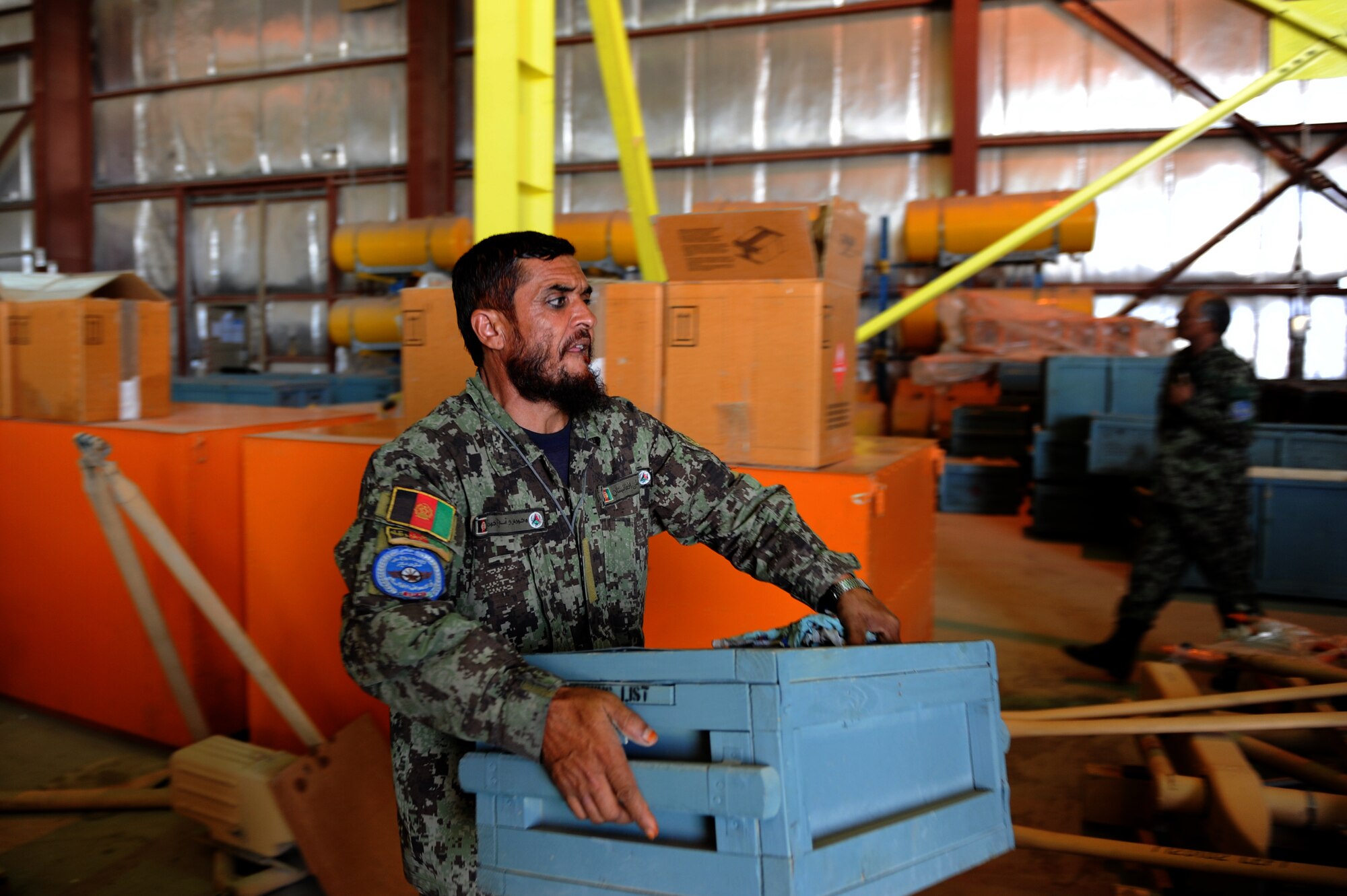 An Afghan soldier carries a crate full of parts at the Kabul, Afghanistan, International Airport. Over the last several months, the Afghan air force has been conducting a project involving the inventory of more than 47,000 parts. Once the inventory is complete, the parts will be distributed to other bases in Afghanistan. (U.S. Air Force photo Staff Sgt. Melissa K. Mekpongsatorn)