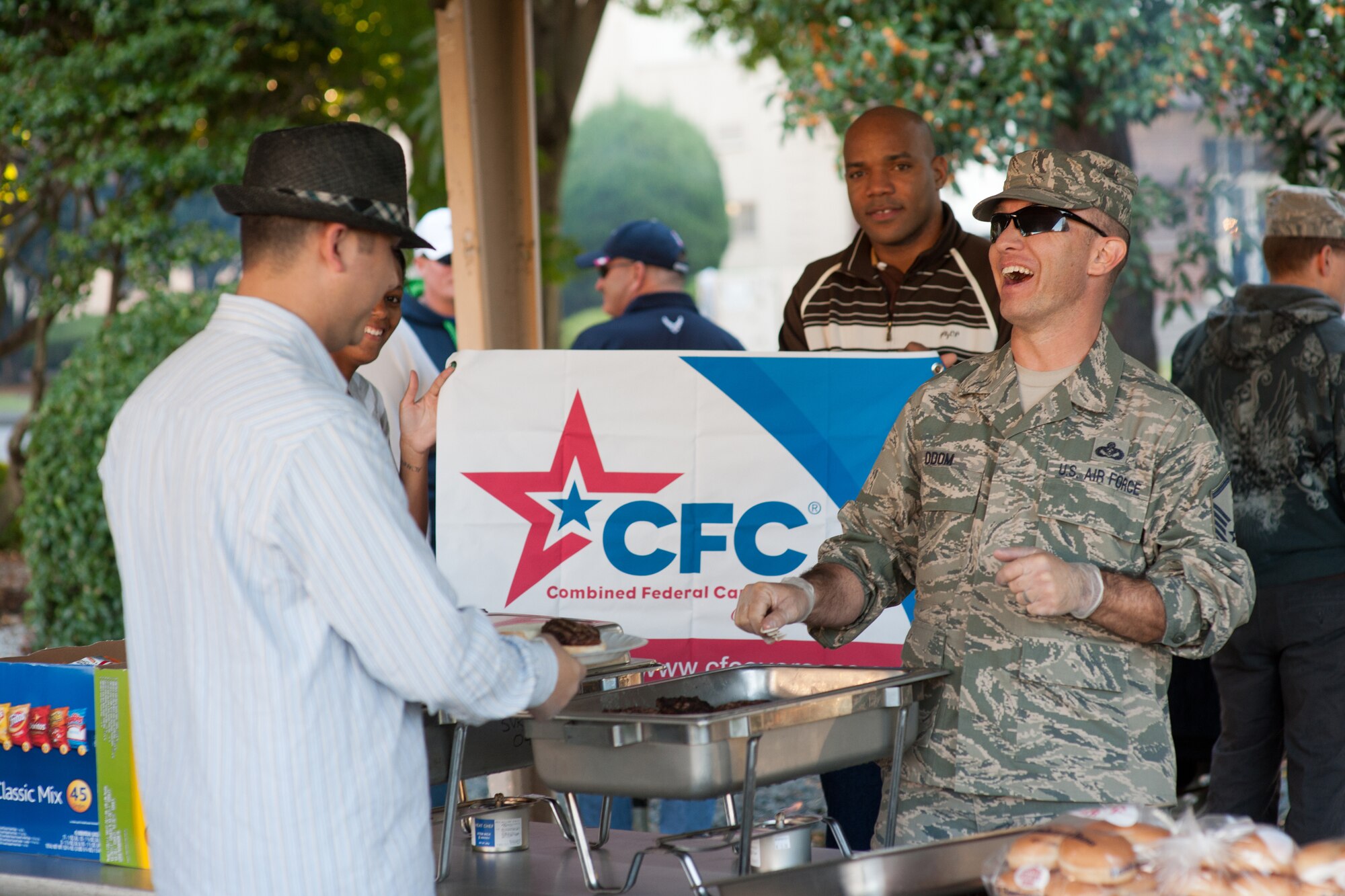 YOKOTA AIR BASE, Japan -- Master Sgt. Dennis Odom, right, 374th Civil Engineer Squadron, serves a burger with a smile during the Combine Federal Campaign-Overseas promotion event at Yokota Air Base, Japan, Oct. 19, 2012. The goal at Yokota is to raise $275,000 for CFC-O. To date, the CFC-O has collected more than 70 percent of the goal. (U.S. Air Force photo by Osakabe Yasuo)