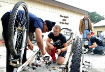 Senior Airman Reese Stock, center, 8th Security Forces Squadron, helps Senior Airman Jareal Gorman, 8th Aircraft Maintenance Squadron, repair a bicycle during Operation Kunsan Rides Oct. 20, 2012, at Kunsan Air Base, Republic of Korea. This is the first of many ACE service projects will which give back to the local community. (U.S. Air Force photo/Senior Airman Brigitte N. Brantley)