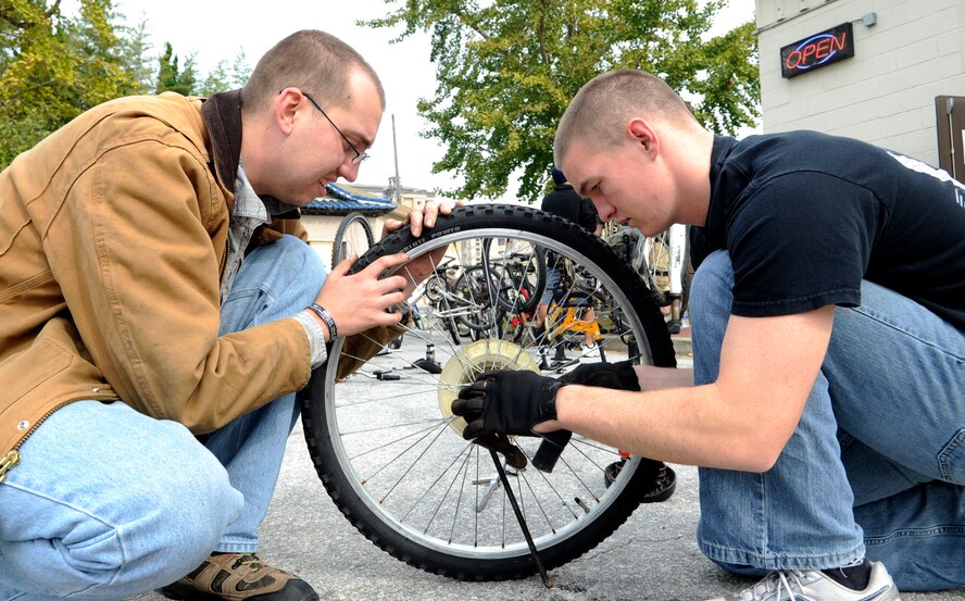 Staff Sgt. Duncan Pugh, left, 8th Logistics Readiness Squadron, and Senior Airman Andrew Deckert, 8th Maintenance Squadron, repair a wheel during Operation Kunsan Rides Oct. 20, 2012, at Kunsan Air Base, Republic of Korea. Many of the bicycles needed only minor repairs while others needed more work such as new inner tubes. (U.S. Air Force photo/Senior Airman Brigitte N. Brantley)