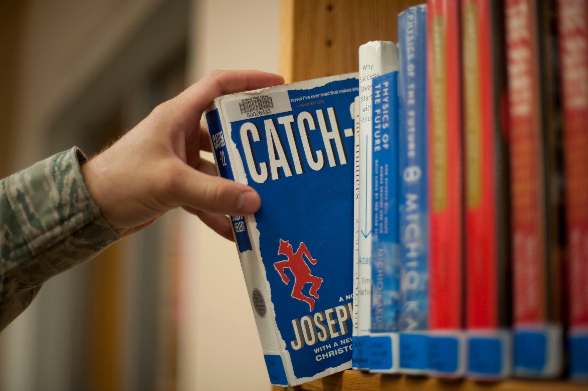 Capt. Jeffrey Larkin, a clinical dentist with the 1st Special Operations Dental Squadron, grabs Catch 22 from a shelf at the Commando Library at Hurlburt Field, Fla., Oct. 12, 2012. Catch 22 is a historical fiction novel by Joseph Heller, a former B-25 bombardier. (U.S. Air Force Photo/Airman 1st Class Hayden K. Hyatt)
