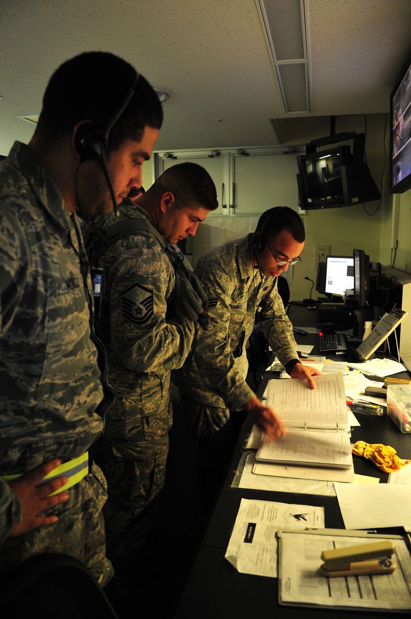 Staff Sgt. John Munoz, base defense operations center controller, Master Sgt. Jason Rangel, of the 18th Security Forces Squadron, and Senior Airman Alex Torres, BDOC controller, reviews checklists during a Pacific Air Forces readiness inspection training scenario on Kadena Air Base, Japan, Oct. 23, 2012. During the readiness inspection, various scenarios are used to test the wing’s ability to respond to a wide range of contingencies. (U.S. Air Force photo/Staff Sgt. Alesia Goosic) 