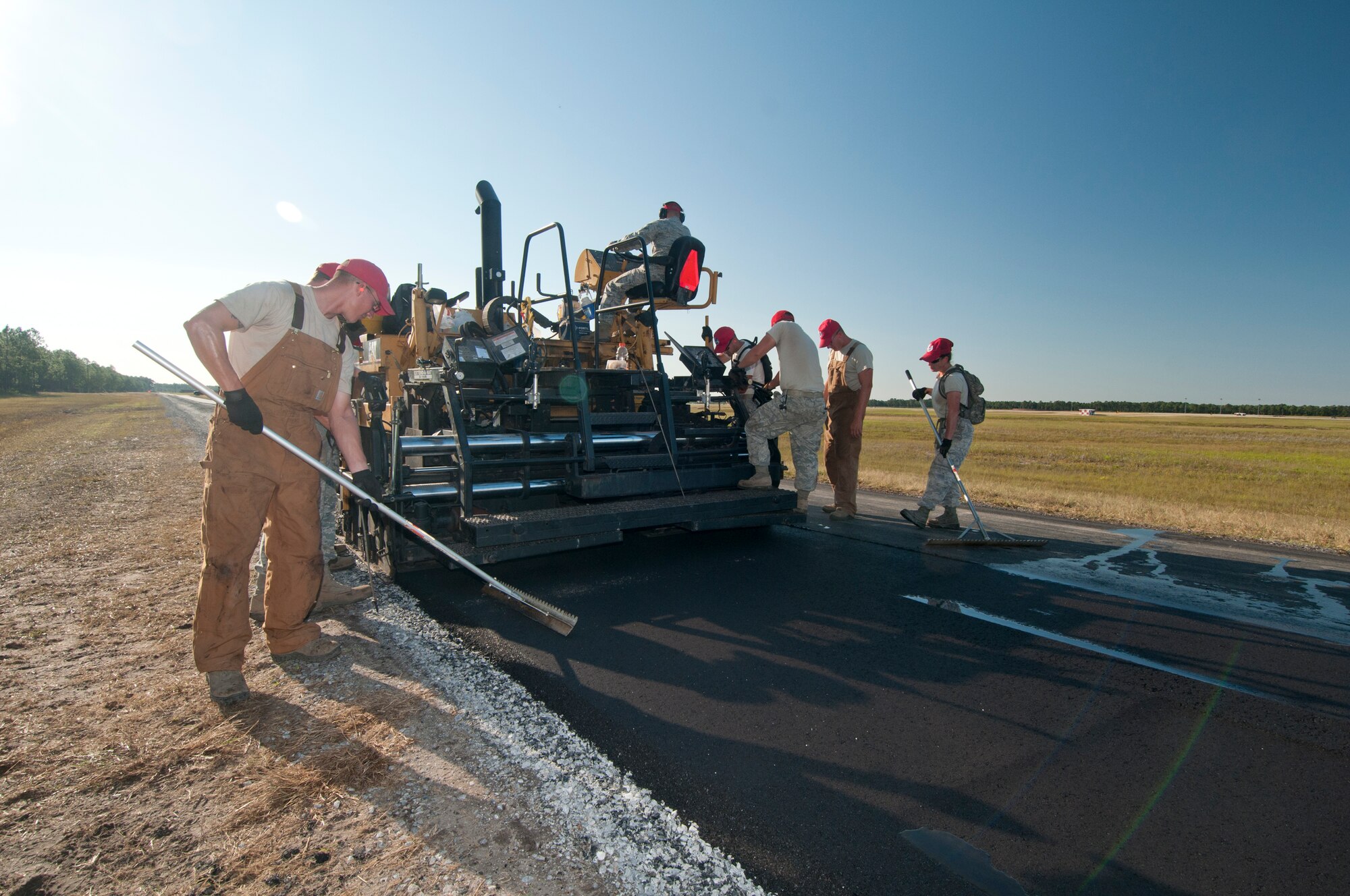 823rd RED HORSE Airmen help even out the asphalt as the paving machine goes by. RED HORSE is conducting paving operations on two miles of road near Tyndall's air field.(U.S. Air Force photo by Chris Cokeing)