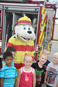 Sparky the Fire Dog poses for a photo with a group of students from the Randolph Elementary School at the Annual Fire Prevention Week demonstration Oct 10. at Joint Base San Antonio-Randolph. Fire Prevention Week was established to commemorate the Great Chicago Fire, the 1871 conflagration that killed more than 250 people, left 100,00 homeless, destroyed more that 17,400 structures and burned more than 2,000 acres. The fire began on October 8, but continued into and did most of its damage on October 9, 1871. (U.S. Air Force photo by Josh Rodriguez)